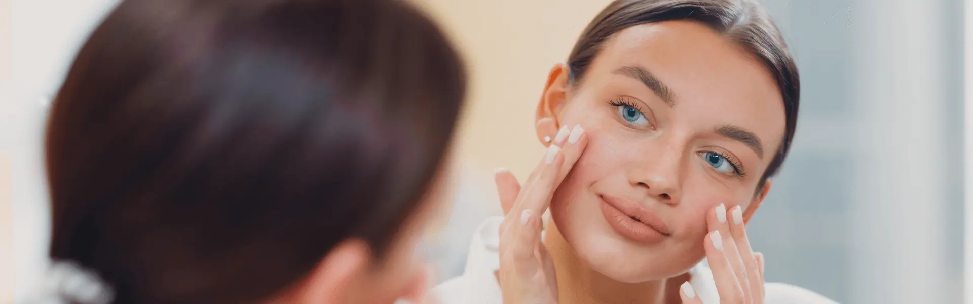 A woman is looking at her face in the mirror.