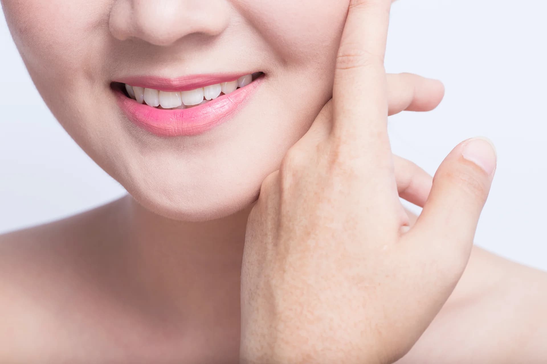 A woman touching her face, specifically her chin, with her hand.