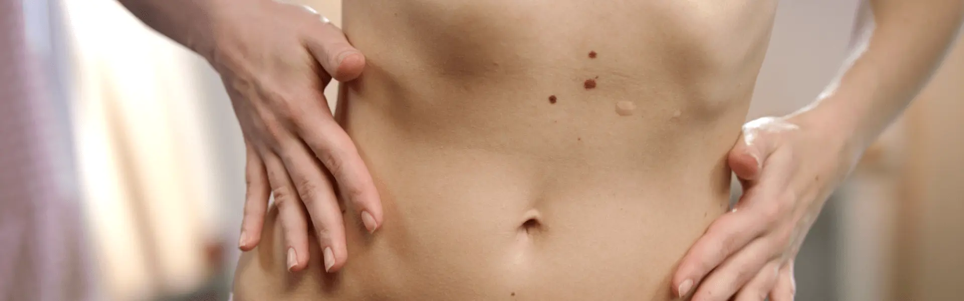 A woman is touching her stomach with her hands.