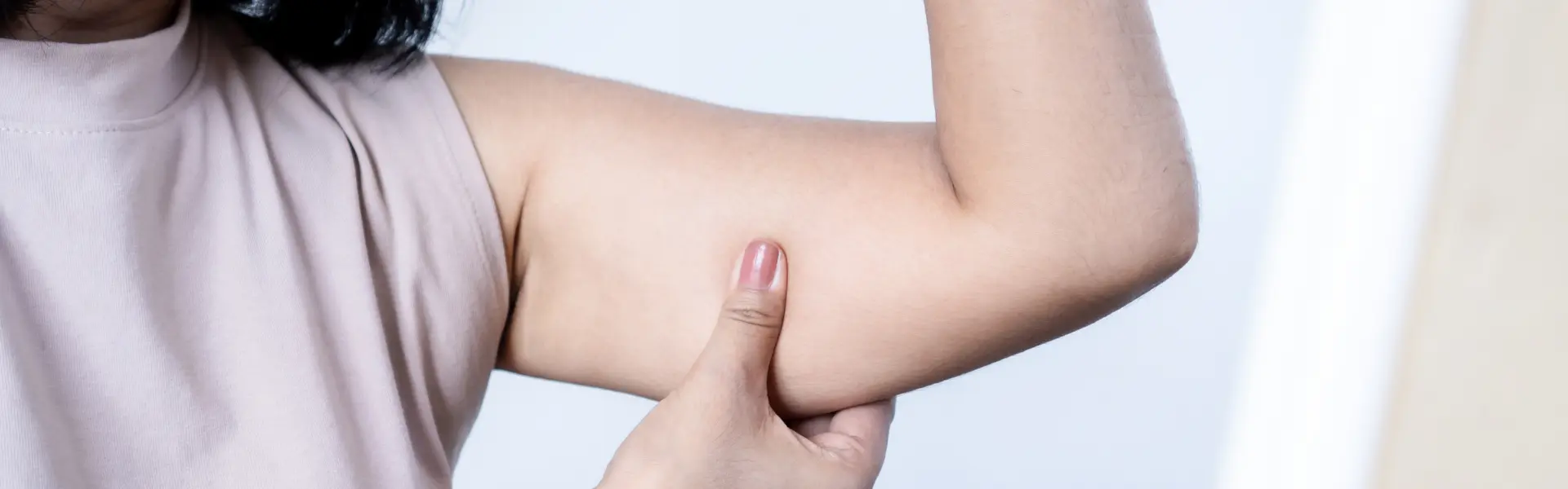 A woman is touching her arm with her hand.