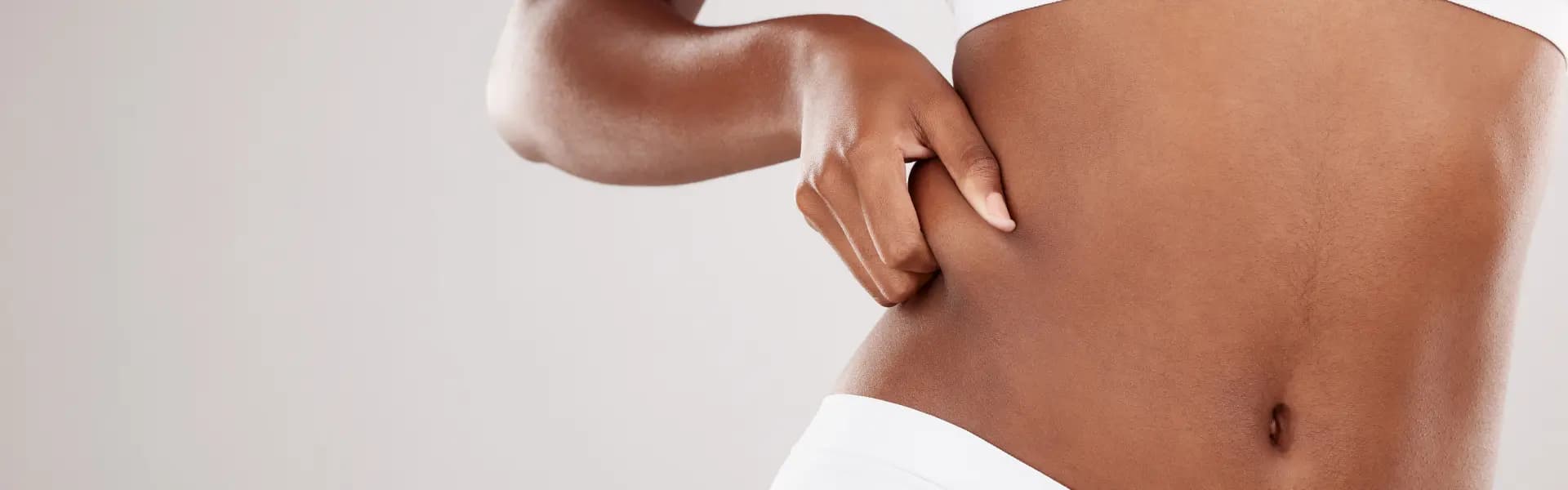 A woman is touching her stomach with her hands.
