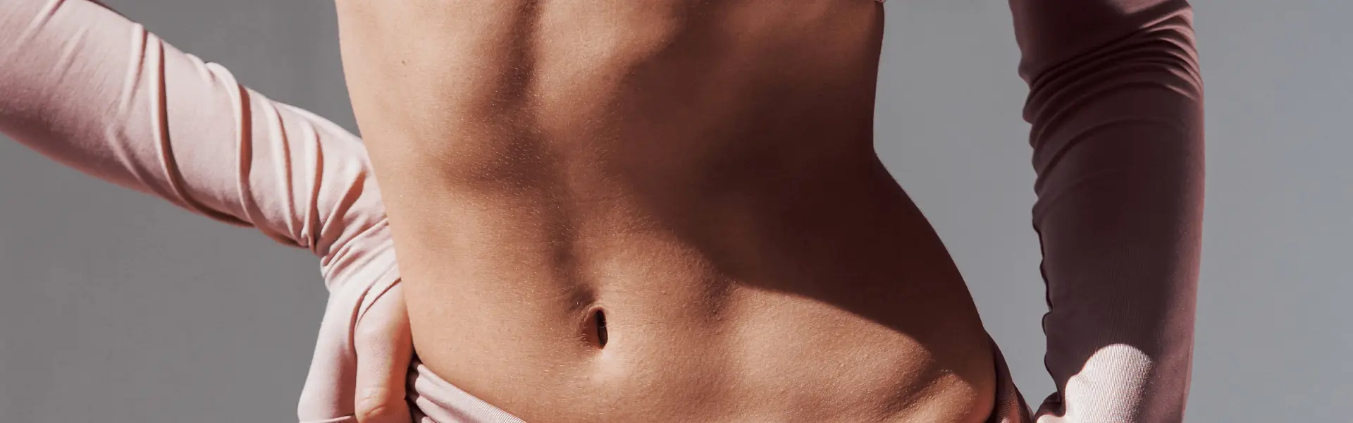 A woman is posing with her hands on her stomach.