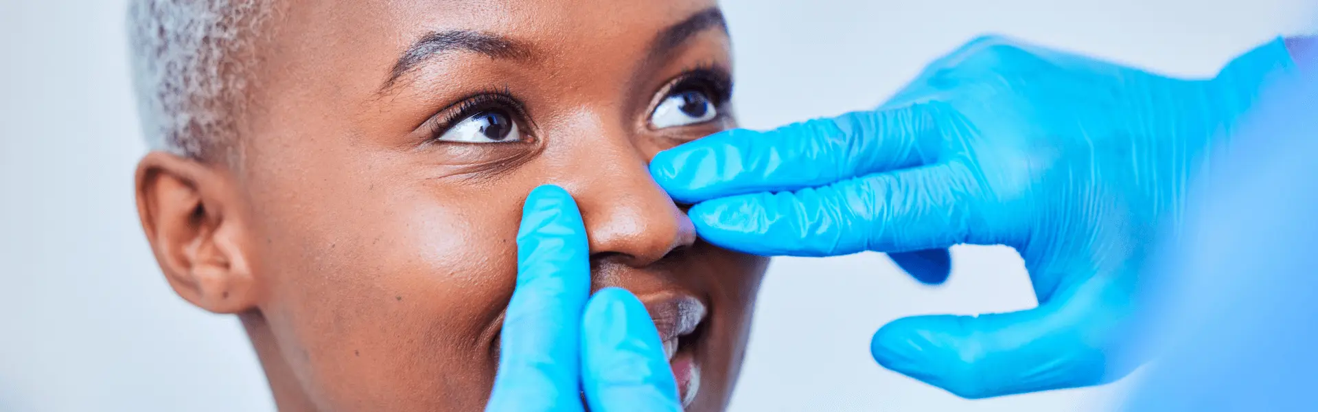 A woman is getting her nose pierced by a doctor.