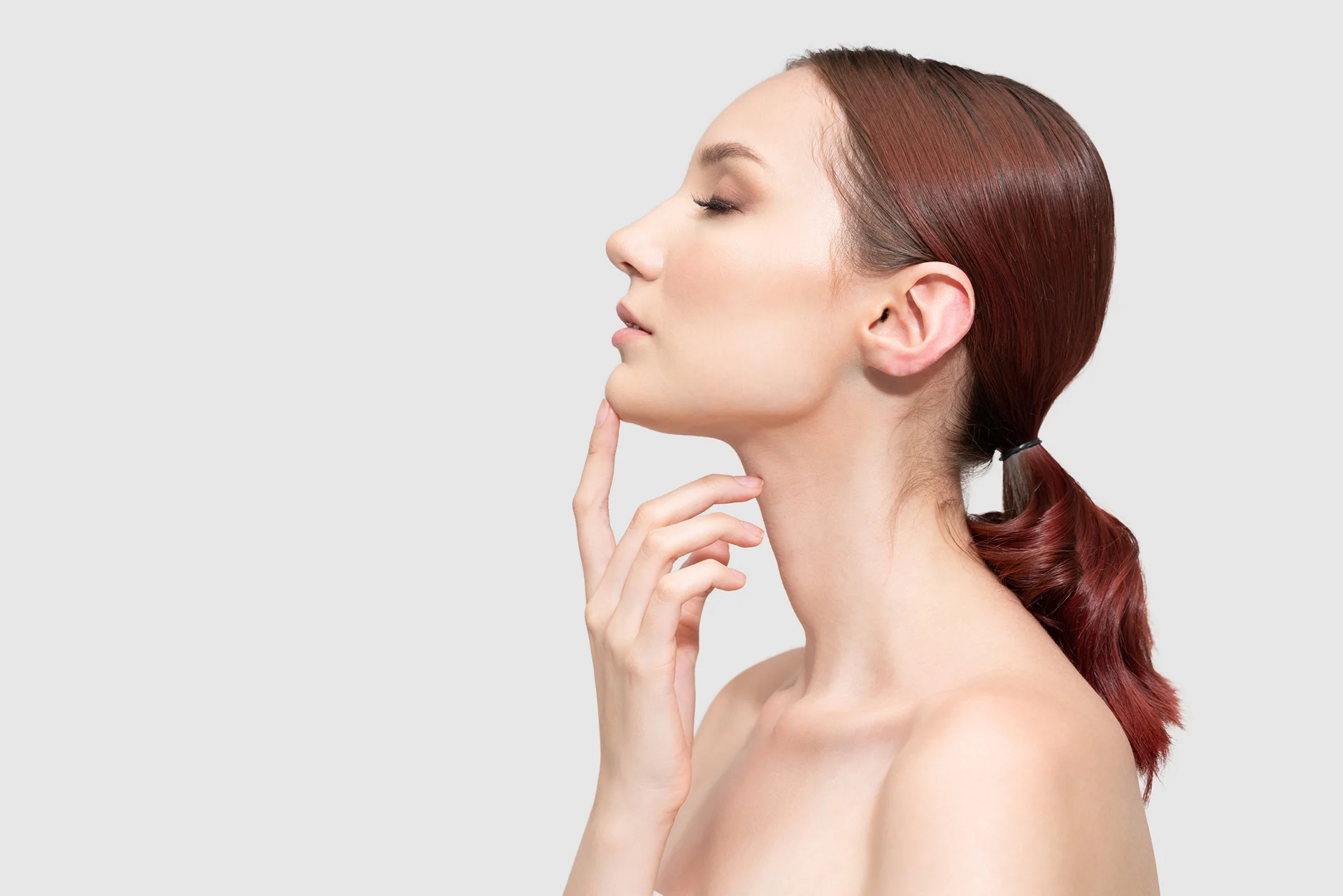 A woman's face with her hand on her chin, exploring the possibilities of managing a chin lipo scar.