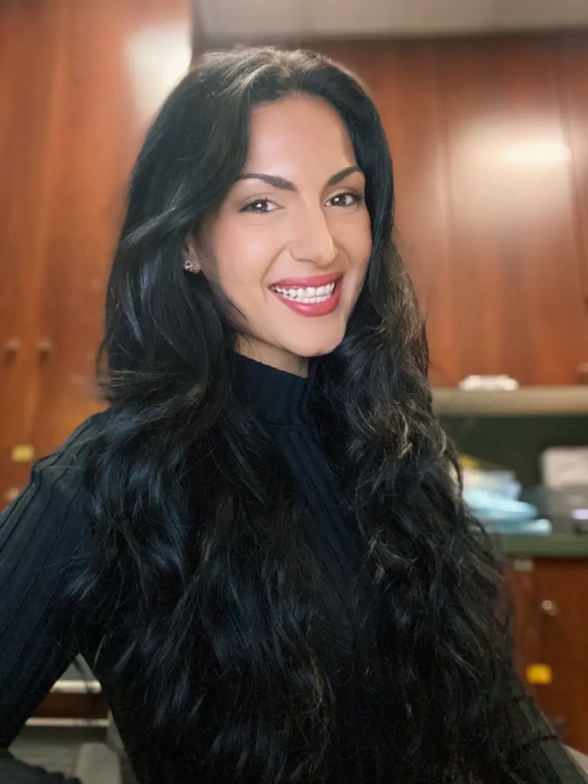 A woman with long black hair smiling for the camera, looking fresh and vibrant for a new day.