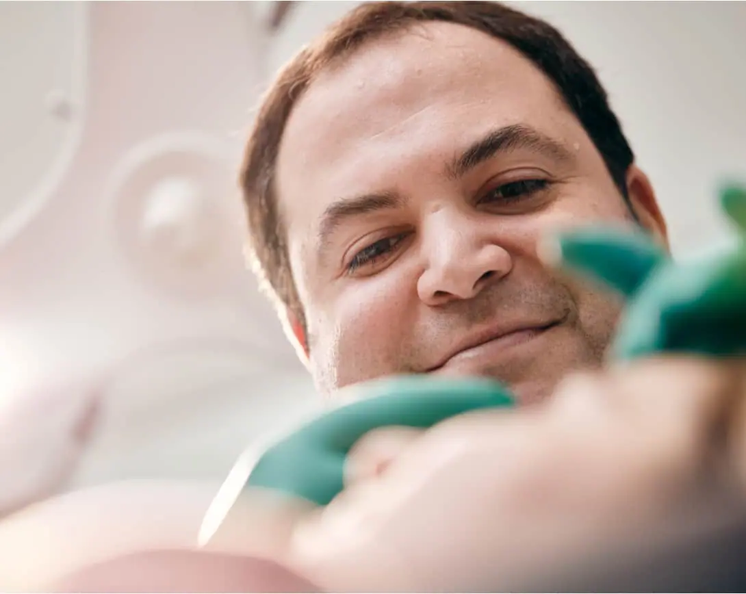 A man smiles as he undergoes a dental examination. [About]