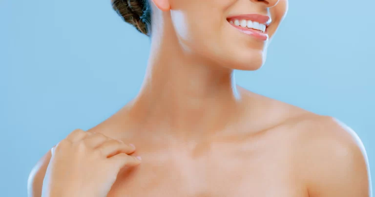 A woman smiling with her hands on her neck after undergoing fibrosis treatment.