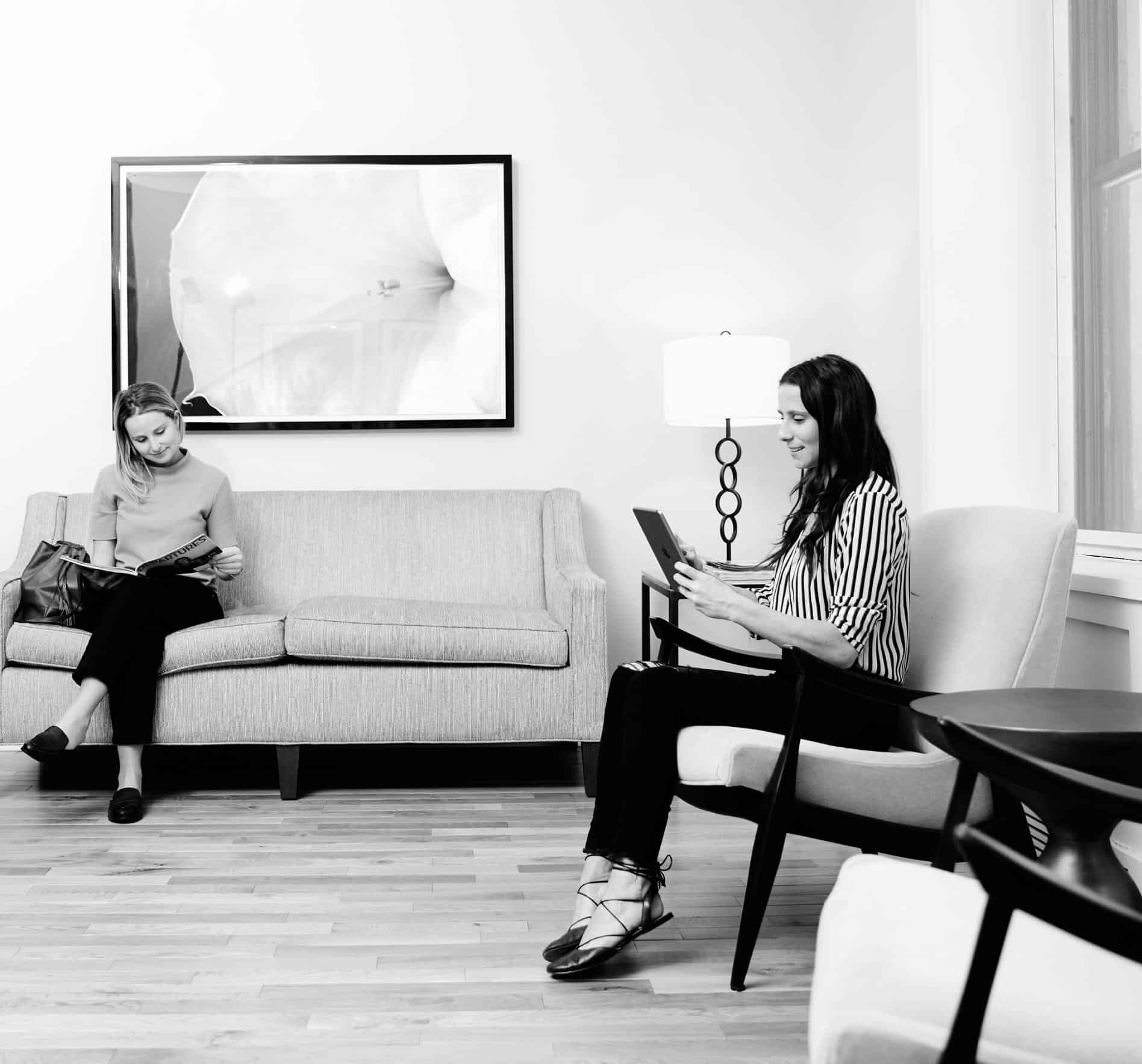 Our practice of capturing moments is showcased in this black and white photo of two women sitting in a room.