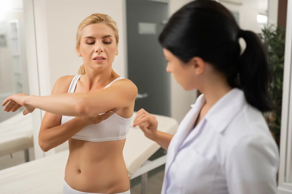 A woman is undergoing an underarm lipo procedure with a surgeon.