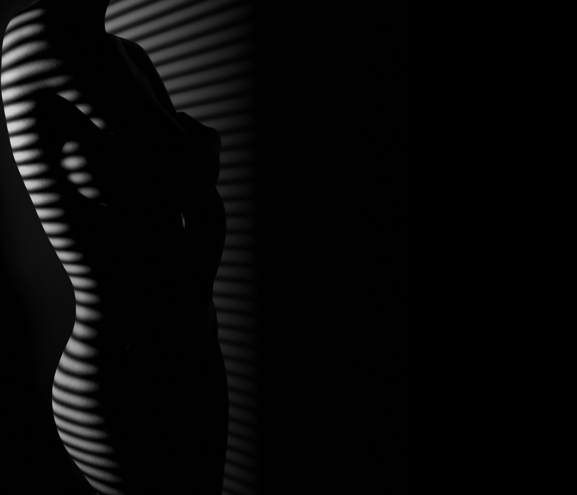 A silhouette of a woman standing in the shadow of a window.