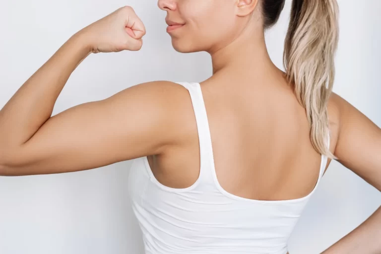A woman flexing her arm in front of a white background.