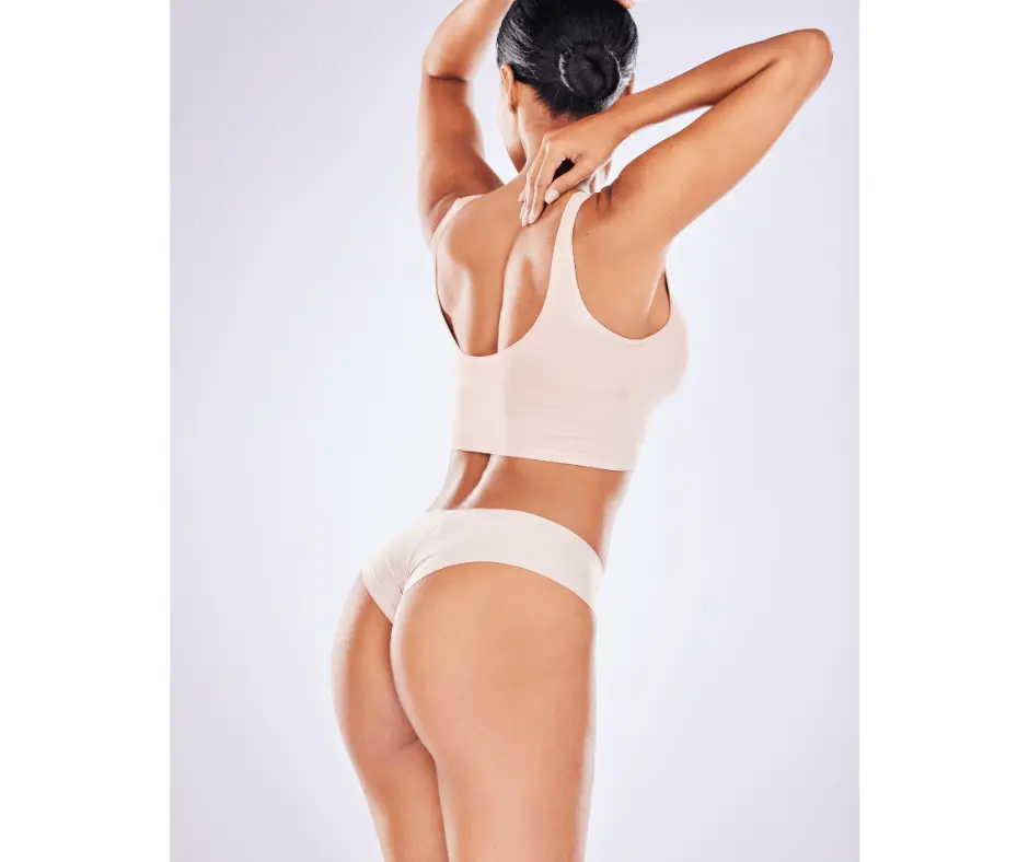 A woman in a nude bikini showcasing her abdomen on a white background.