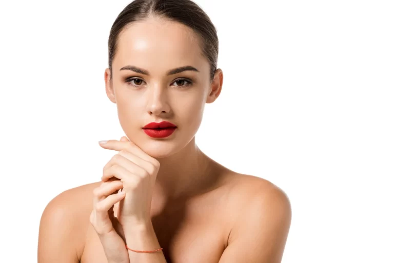 Woman with red lipstick striking a pose on a white background, emphasizing her contoured chin after chin liposuction.