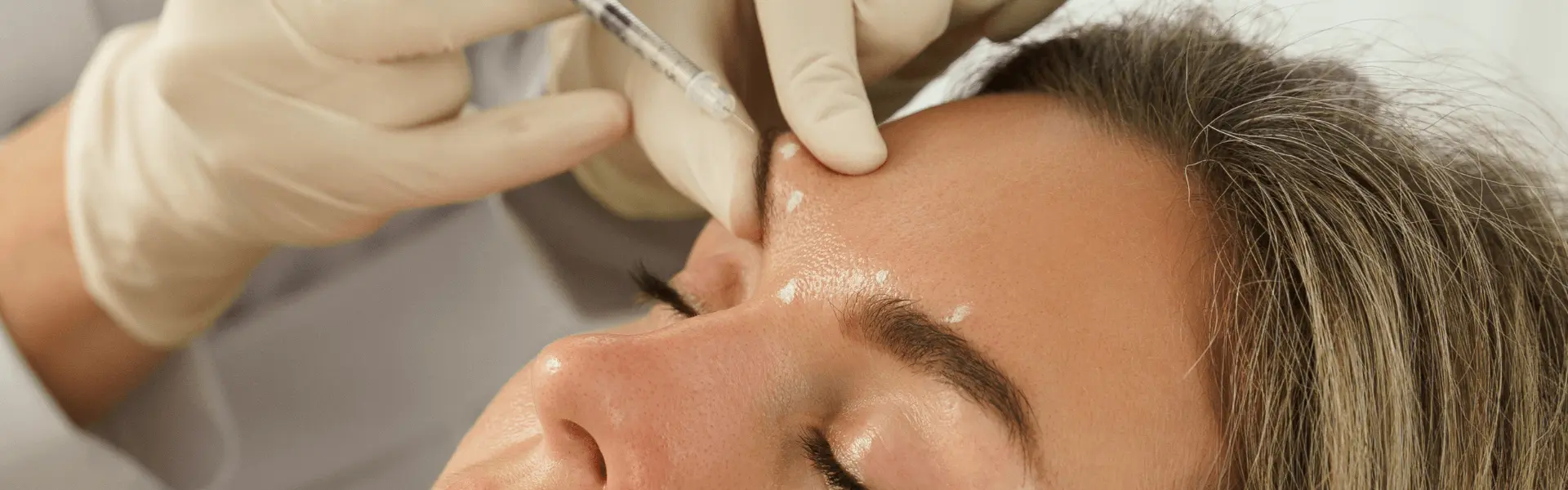 A woman getting her eyebrows injected by a doctor.