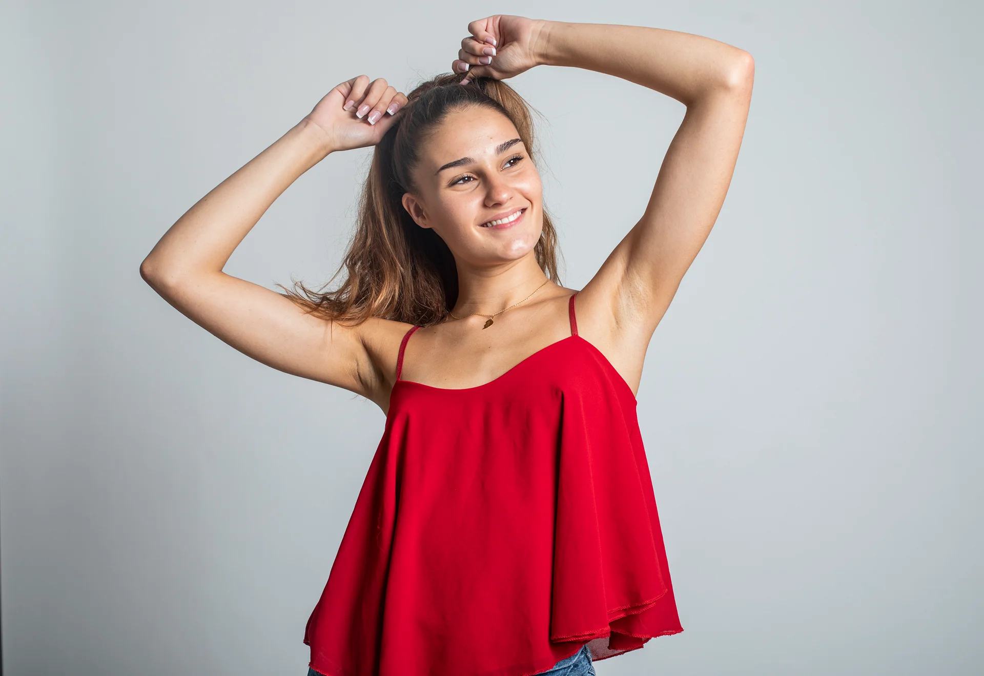 A young woman in a red top showcasing her sleek arms after arm lipo procedure.