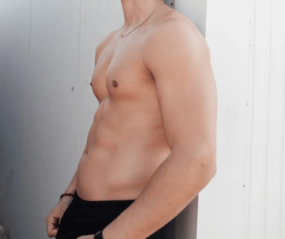 A shirtless man leaning against a wall in a large volume space.