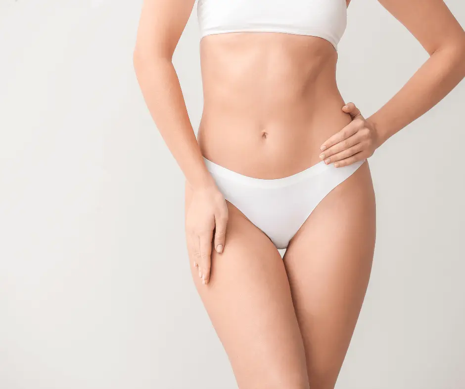 A woman in a white bikini striking a confident pose with her hands on her hips, showcasing the results of her Lipo 360 procedure.