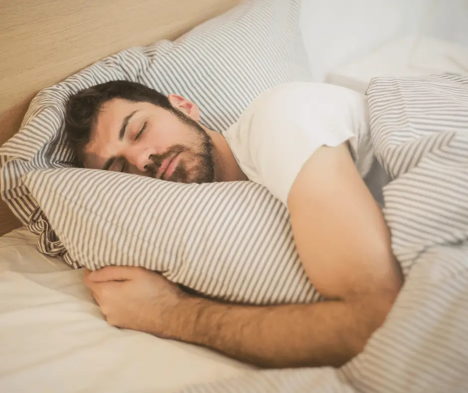 A man sleeping peacefully in a bed with white sheets, completely unaware of the transformative 360 experience he had earlier during the Lipo process.
