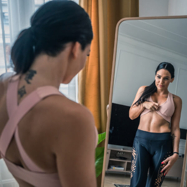 A woman in a sports bra admiring her reflection in the mirror.