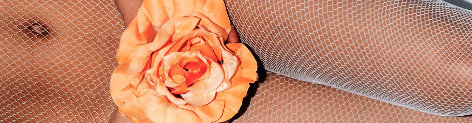 A close up of a woman in fishnet stockings with a flower.