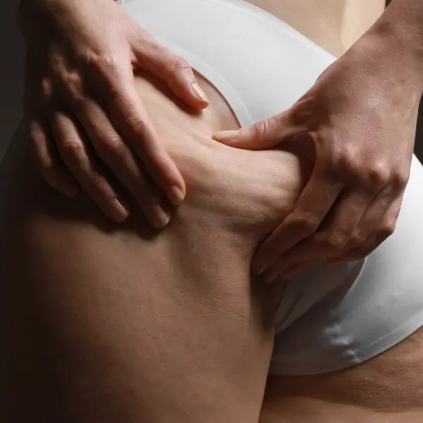 A woman is touching her stomach with her hands.