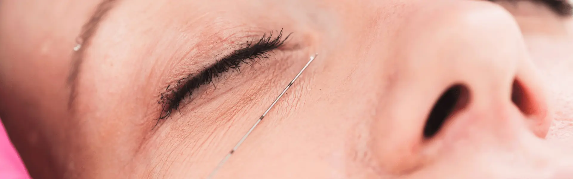 A close up of a woman's eye with a needle.