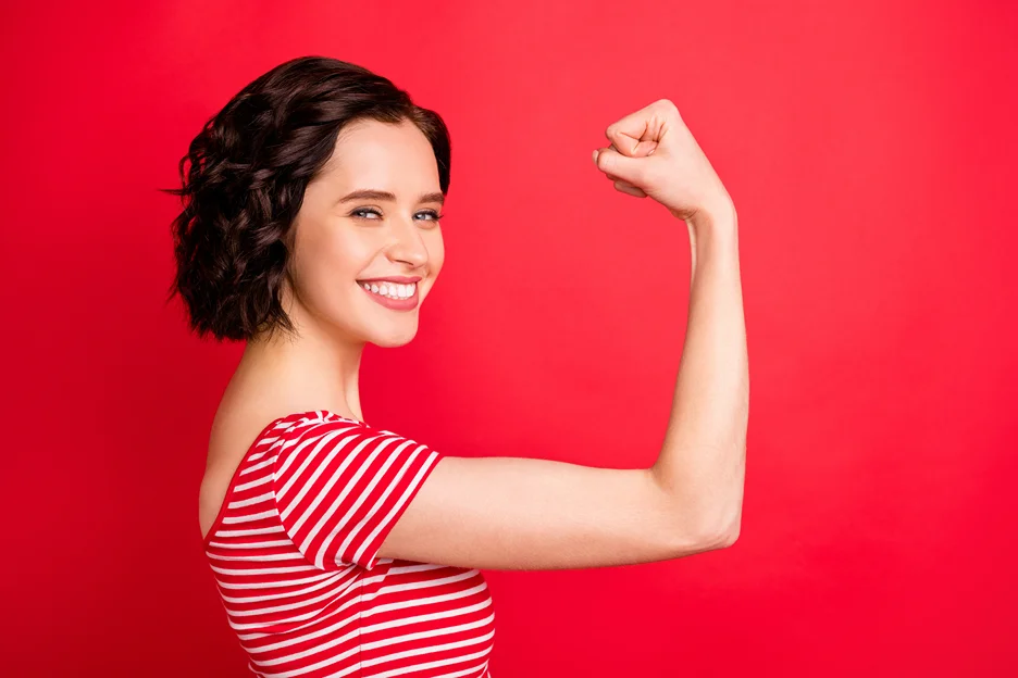 A young woman showcasing her toned arm after VASER arm lipo against a vibrant red background.