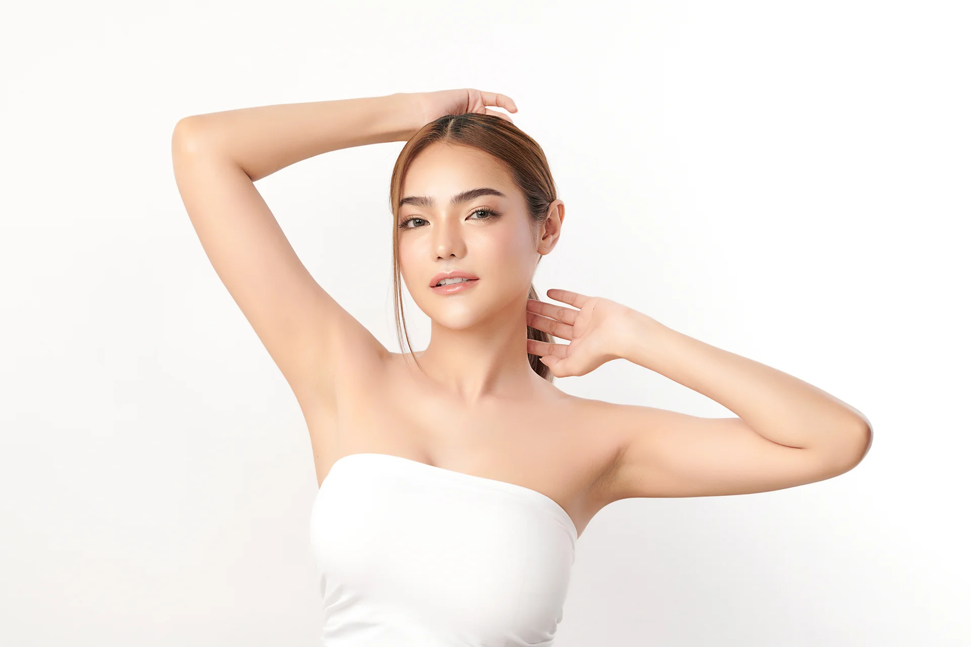 A woman in a white dress striking a pose for a photo, showcasing her precise arm fat removal achieved through VASER lipo arm lifts.