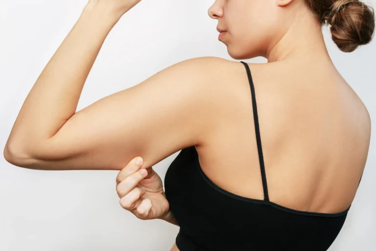 A woman is flexing her arm, showing off her toned muscles.