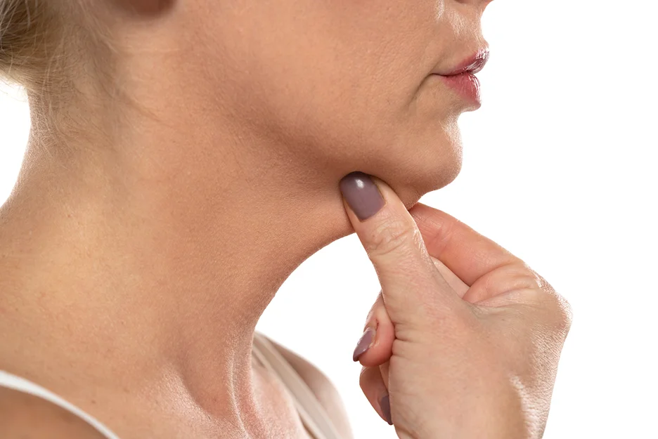 A woman is touching her neck with her finger, concerned about her double chin.
