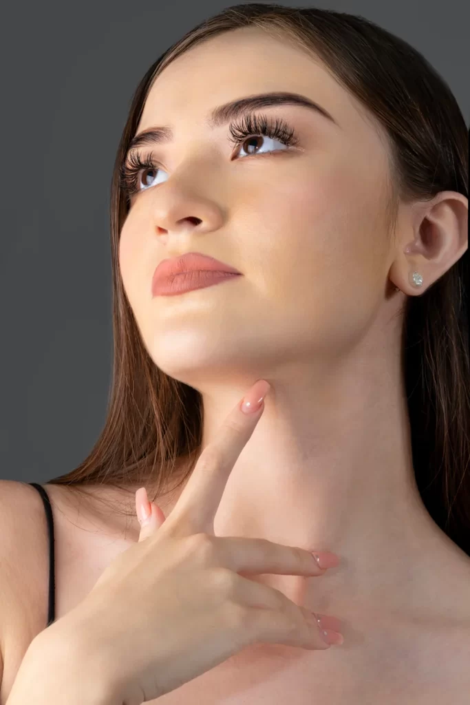 A woman with her hand on her neck undergoing chin liposuction.