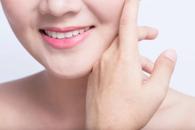 A woman touching her face, specifically her chin, with her hand.