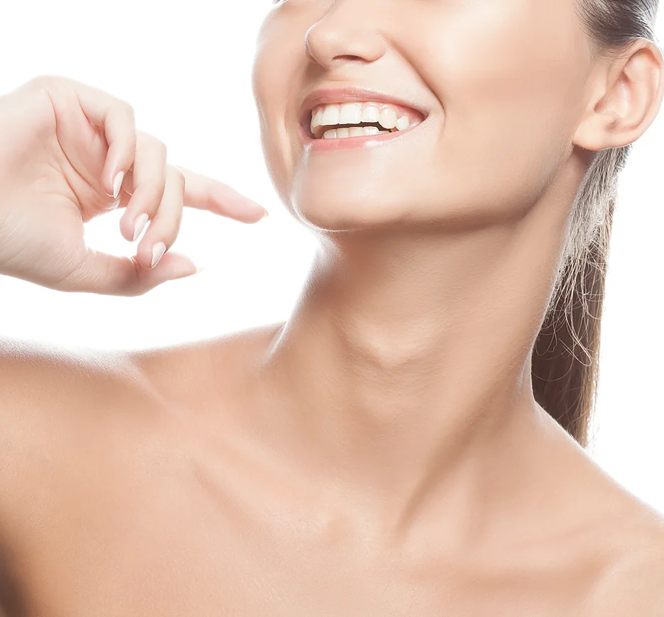 A woman is smiling with her finger on her defined jawline.