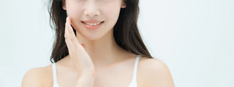 A young asian woman with a sculpted look, her hand on her face.