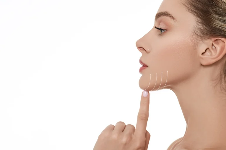 A woman, contemplating chin liposuction, with her finger on her face.